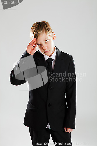 Image of Serious young boy in black suit saluting