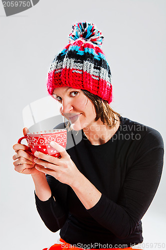 Image of Smiling woman in knitted hat holding cup