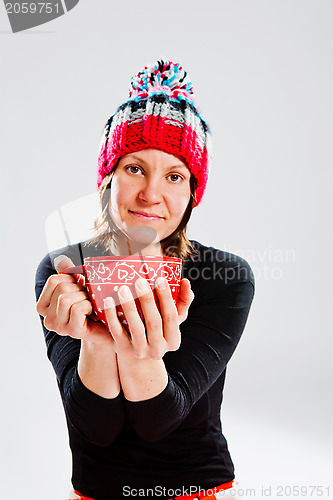 Image of Smiling woman in knitted hat holding cup