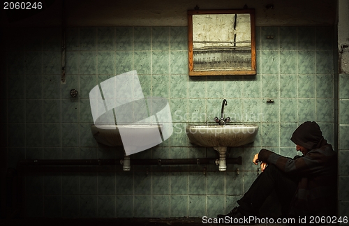 Image of An abandoned industrial interior with a depressed man