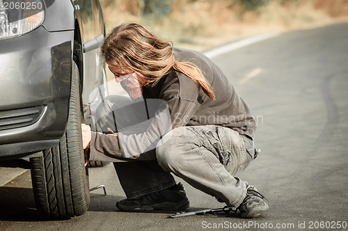 Image of Young man repairing car outdoors