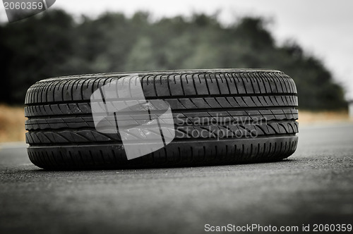 Image of Abandoned car tyre on the road with green background