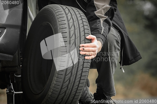 Image of Young man repairing car outdoors