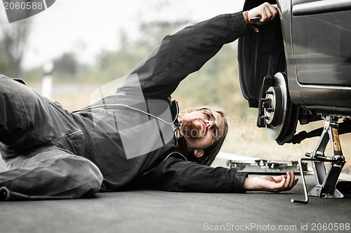 Image of Handsome young man repairing car