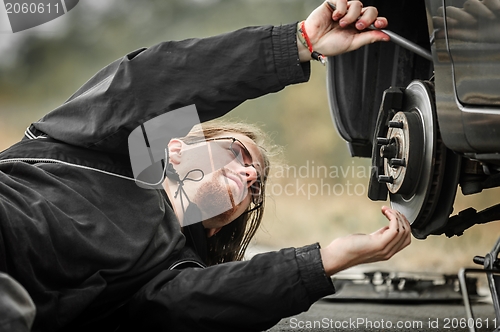 Image of Handsome young man repairing car