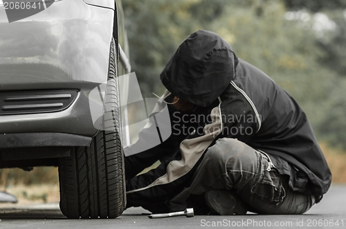 Image of Young man repairing car outdoors