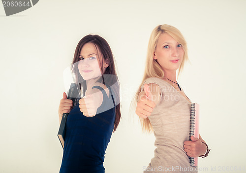 Image of Two beautiful student girls showing thumbs up