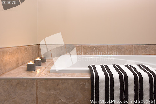 Image of Bathtub, striped towel and candle lights