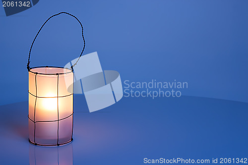 Image of Cozy lantern on blue winter background