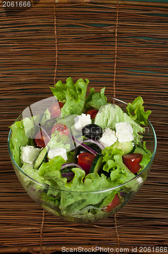Image of Salad in a glass bowl on a wooden base