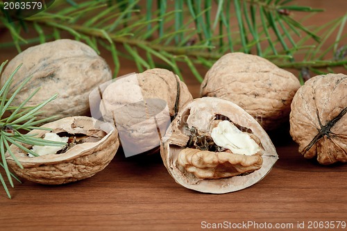 Image of walnuts and a cracked walnut on wooden background