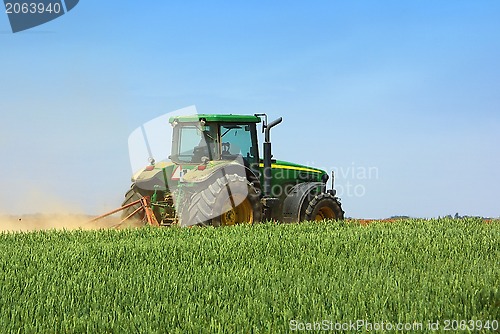 Image of Green tractor working in the field. 