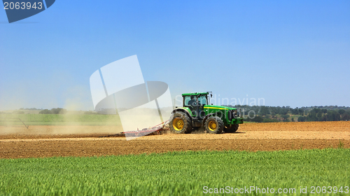 Image of Green tractor working in the field. 