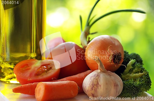 Image of Olive oil and vegetables in green background.