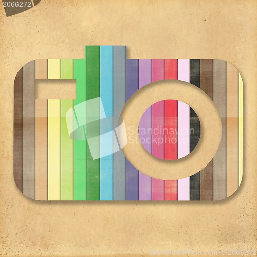 Image of retro camera icon with rainbow colors on cork board background 