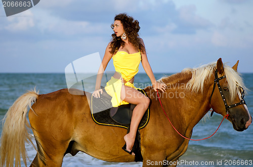 Image of Pretty young woman riding a horse