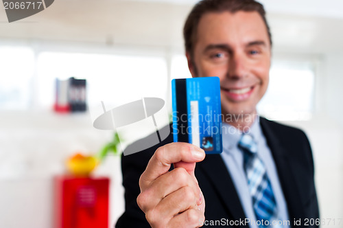 Image of Cheerful businessman holding up his credit card