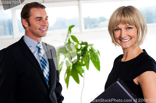 Image of Handsome boss passing by smiling female colleague