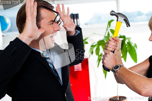 Image of Woman threatening her boss, holding hammer.