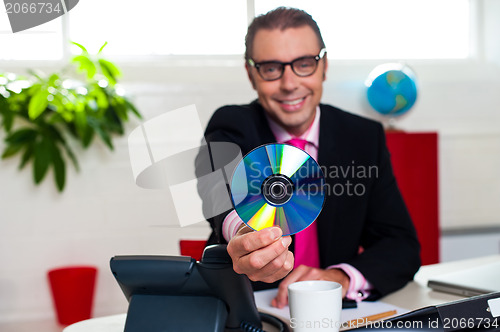 Image of Bespectacled boss presenting a compact disk