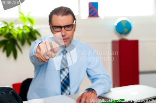 Image of Serious manager pointing at you from his work desk