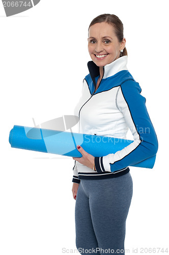 Image of Woman carrying blue yoga mat