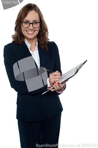 Image of Corporate woman in eyeglasses writing on clipboard