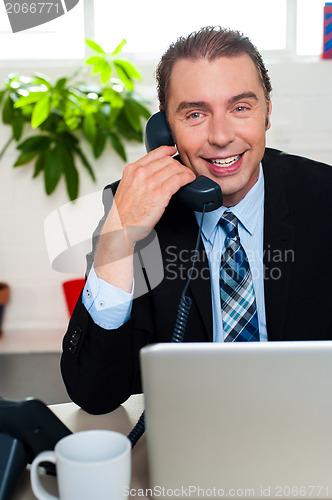 Image of Smiling male manager attending clients call