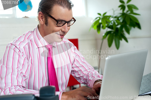 Image of Busy employee in office working on laptop