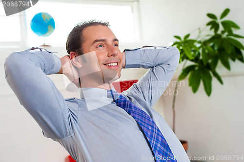 Image of Young businessman relaxing and day dreaming
