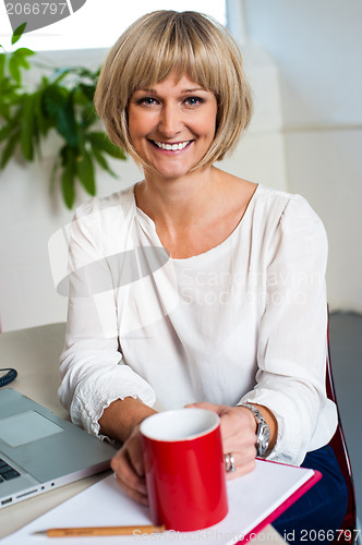 Image of Casual woman in office enjoying her coffee break