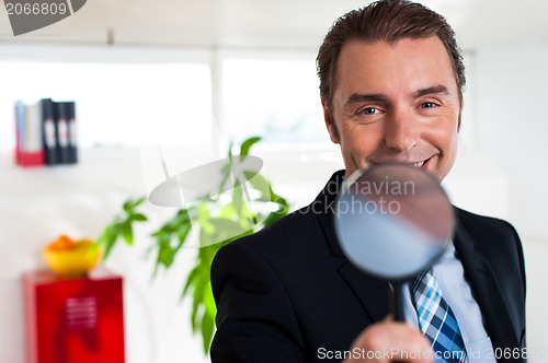 Image of Business executive holding magnifying glass