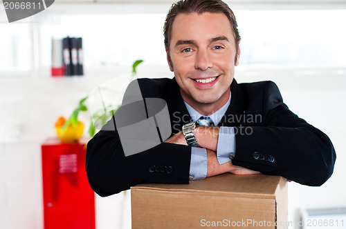 Image of Handsome businessman leaning on packed carton