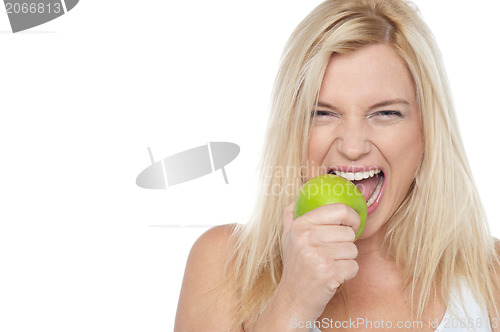 Image of Closeup shot of a blonde woman biting an apple