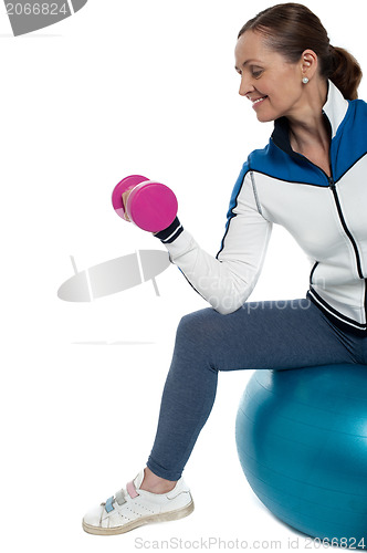 Image of Woman on swiss ball working out with dumbbells