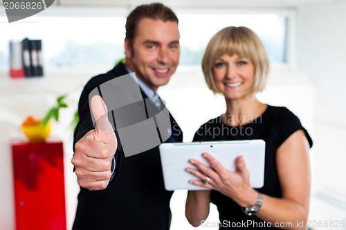 Image of Secretary with a tablet posing with her successful boss