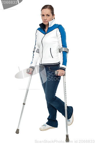 Image of Pensive looking woman using crutches to walk