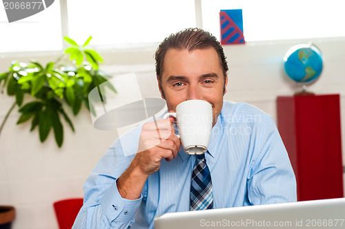 Image of Smiling male manager enjoying hot coffee