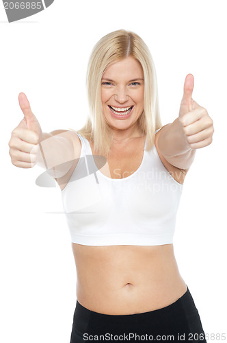 Image of Fit woman in sports bra gesturing double thumbs up