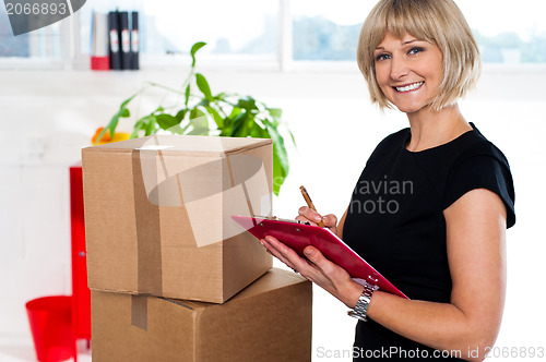 Image of Casual woman documenting list of goods on clipboard