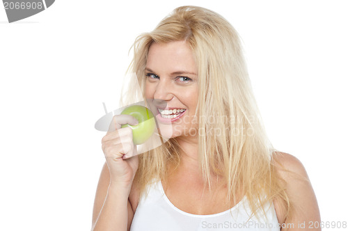 Image of Health conscious woman about to take bite from green apple