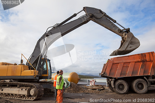 Image of Excavator bucket on a dump truck lifted