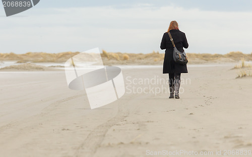 Image of Lonely woman walking on a beach