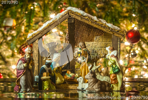 Image of Old handmade nativity scene in front of a christmas tree