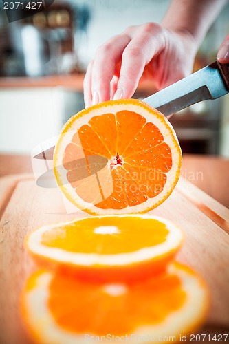 Image of Woman's hands cutting orange