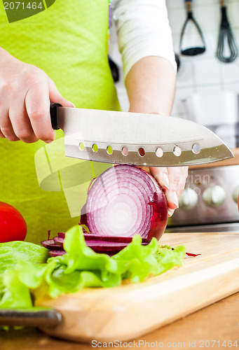 Image of Woman's hands cutting bulb onion