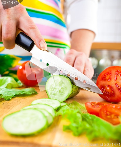 Image of Woman's hands cutting cucumber