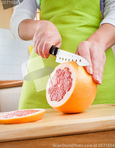 Image of Woman's hands cutting grapefruit