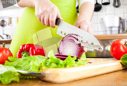 Image of Woman's hands cutting bulb onion