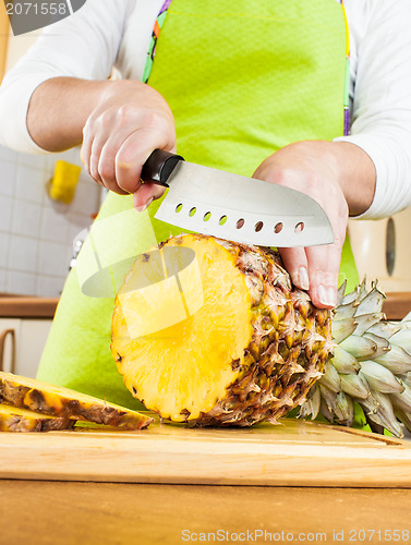 Image of Woman's hands cutting pineapple